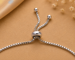 Load image into Gallery viewer, Close-up of a sterling silver adjustable bracelet with a yellow enamel flower charm accented by a cubic zirconia stone.