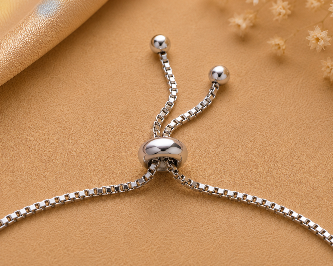Close-up of a sterling silver adjustable bracelet with a yellow enamel flower charm accented by a cubic zirconia stone.
